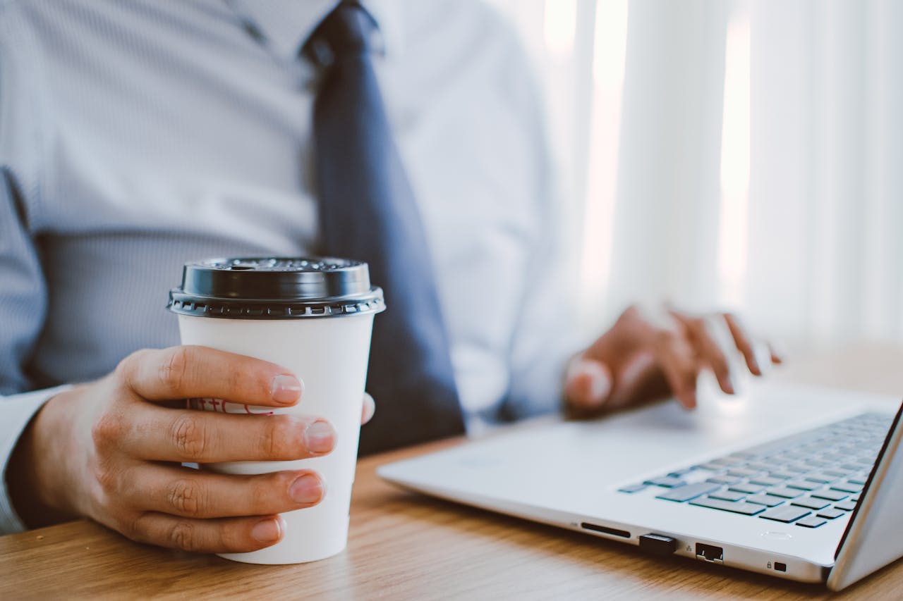 services-04 Business professional working remotely, enjoying coffee while using a laptop indoors.